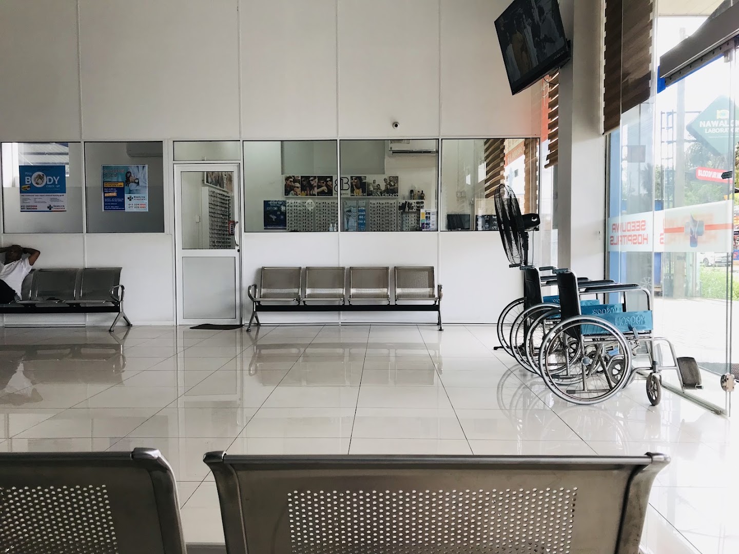 Interior seating and wheelchairs near the glass entrance at Seeduwa Hospitals